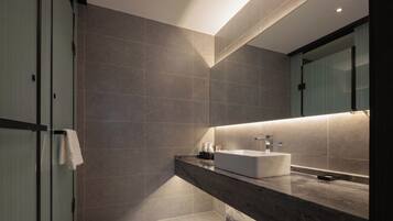 A modern bathroom with a large mirror, a white sink, and a glass shower enclosure.