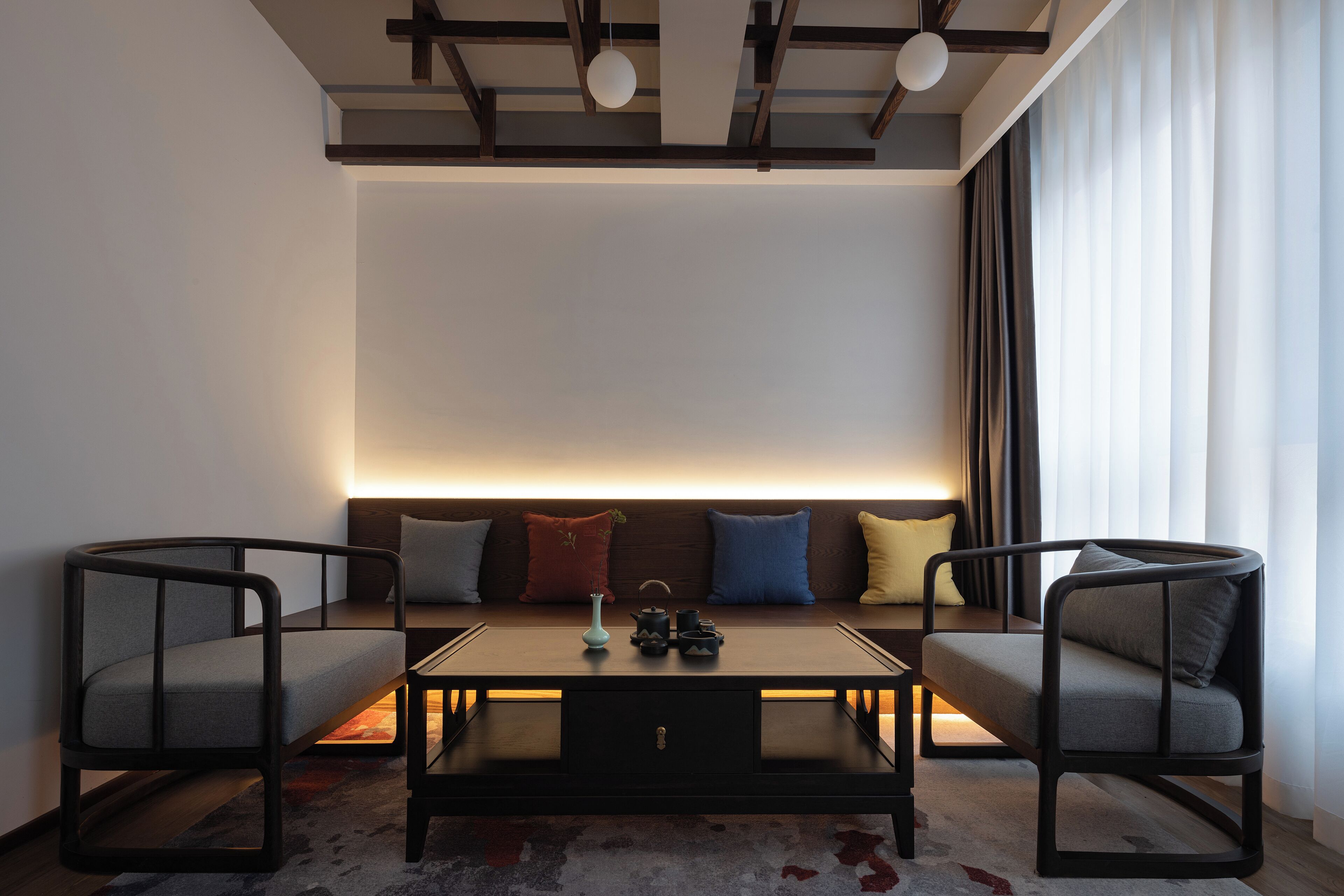 A modern living room with a sofa, two armchairs, a coffee table, and a ceiling light fixture.