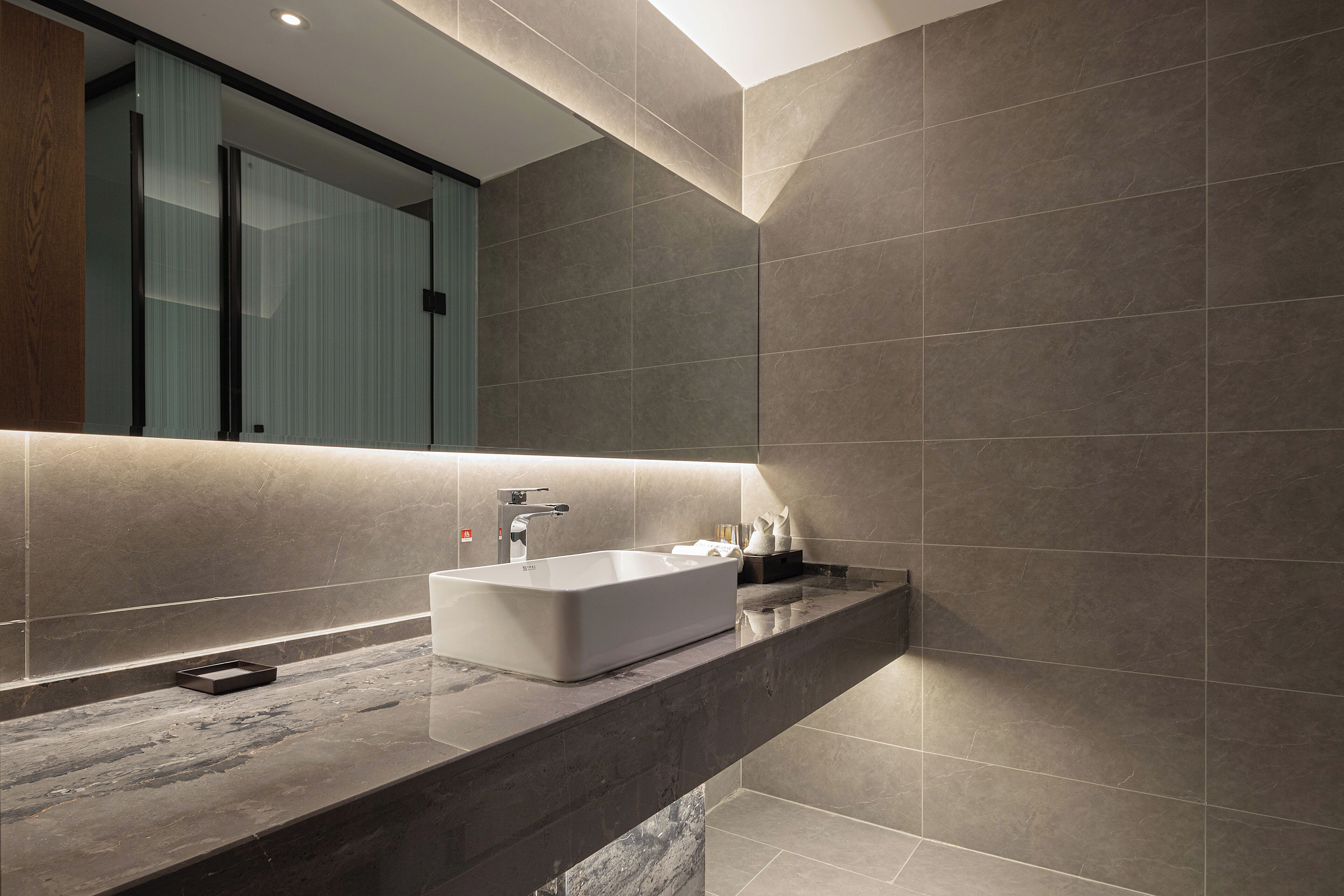 A modern bathroom with a rectangular sink, a mirror, and a dark marble countertop.