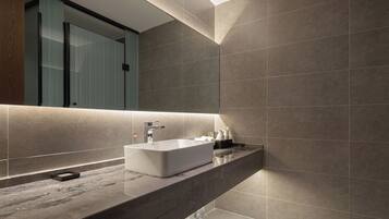 A modern bathroom with a rectangular sink, a mirror, and a dark marble countertop.