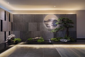 A modern interior with a stone wall, a circular mirror, and a minimalist water feature. - Qianna Hotel Xi'an Bell Tower (Xi'an)