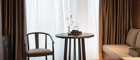Una habitación de hotel con una cama, una silla, una mesita con un jarrón y una tetera, y un sofá.