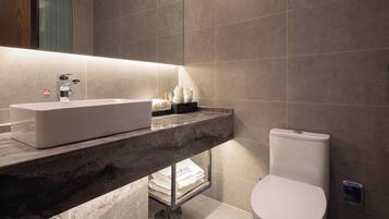 Un baño moderno con encimera de mármol, un lavabo blanco y un inodoro.