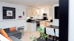 A modern apartment with a living area, kitchenette, and dining space.