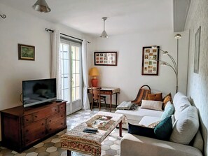 A living room with a television, a sofa, a coffee table, a desk, and a chair. - Charming gîte with swimming pool south Ardèche L'Oustal (Vesseaux)