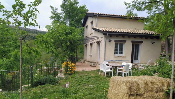 A house with a patio, outdoor seating, and a fenced garden. - Charming gîte with swimming pool south Ardèche L'Oustal (Vesseaux)