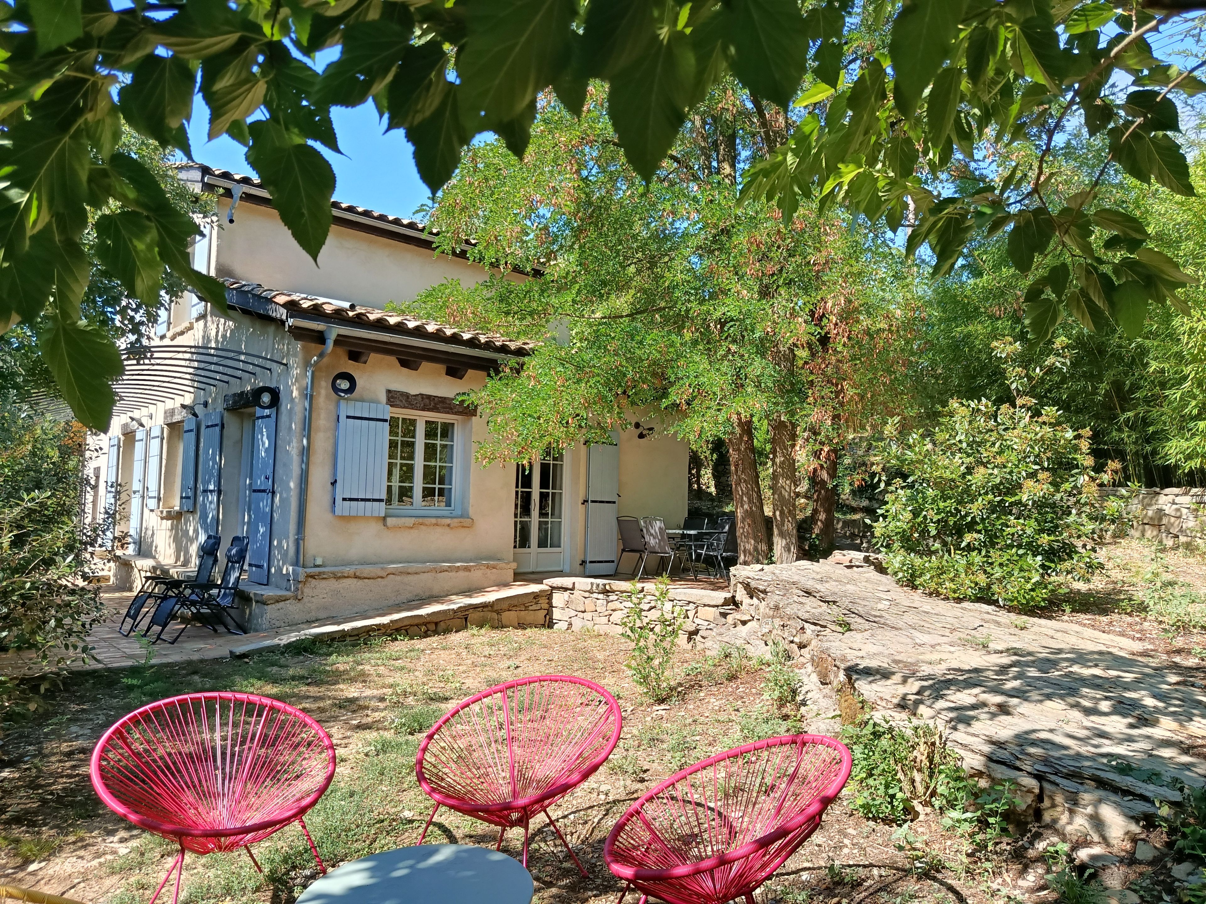 Una casa con un patio, una mesa de comedor y tres sillas rojas.