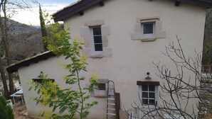 A two-story building with multiple windows, a ladder, and a small balcony. - Charming gîte with swimming pool south Ardèche L'Oustal (Vesseaux)