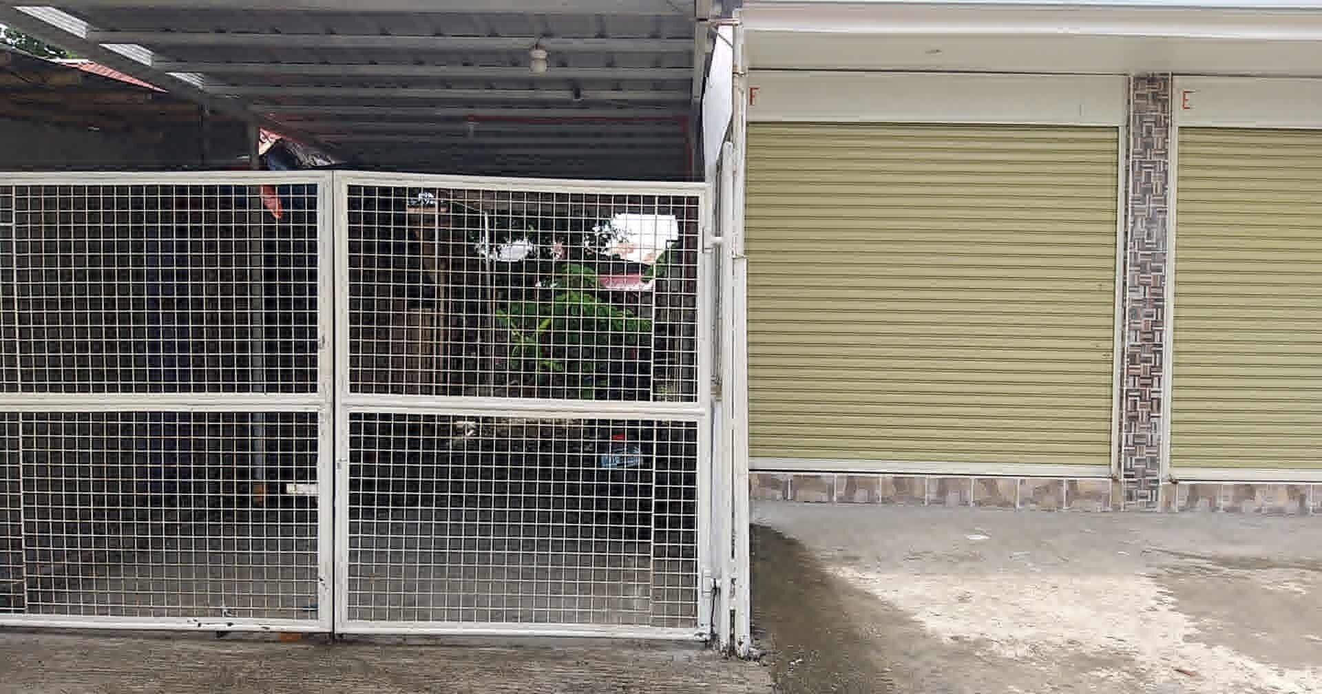Metallinen portti, jossa on ruudukkomainen kuvio, suljettu säleverho-ovi ja betonipohja.