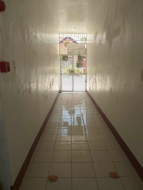A corridor with a tiled floor leading to a gated entrance.