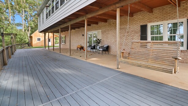 Une terrasse extérieure couverte, avec un banc en bois, une petite table roulante et une table avec des chaises.