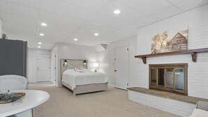 Une chambre à coucher avec un lit, une cheminée, un mur blanc et une porte.