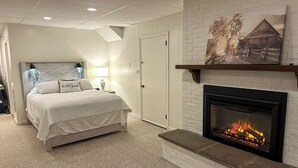 Une chambre à coucher comprenant un lit, une cheminée, une porte et une œuvre d’art accrochée au mur.