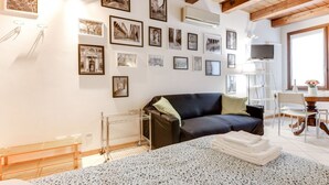 Ein modernes Zimmer mit einer schwarzen Couch, einem Esstisch und einem Fernseher.