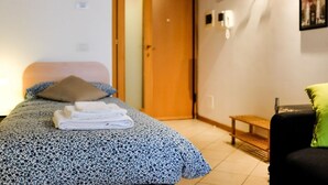 Ein Schlafzimmer mit einem Bett, einer Sitzbank, einer Tür und Wandleuchten.