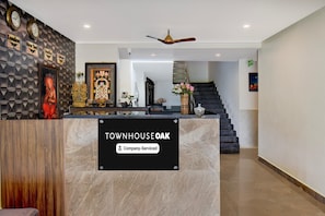 Un espace d’accueil doté d’un comptoir en marbre, de horloges, de tableaux encadrés et d’un escalier.