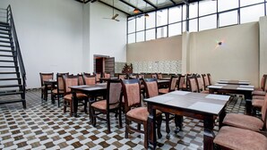 Een vergaderruimte met tafels, stoelen, een trap en een groot raam met natuurlijk licht.