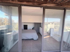 Une chambre à coucher avec un lit, une petite table de chevet et une fenêtre donnant sur des immeubles.