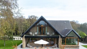A modern house with a large patio, outdoor furniture, and a glass conservatory. - Luxury Golf House near Royal Birkdale (The Open) | Hot Tub | Sleeps 12+ (Southport)