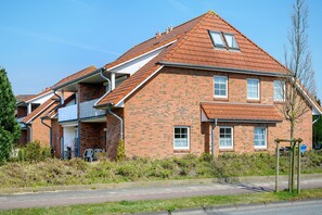 Ein zweigeschossiges Backsteinhaus mit geneigtem Dach, einem sichtbaren Schornstein und einem kleinen Garten mit einem Fahrrad.