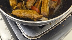 Eine Pfanne mit Fleisch und Tomatenscheiben auf einem Herd.