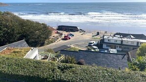 Vista sulla costa con un’area di parcheggio, edifici e una strada che conduce alla spiaggia.