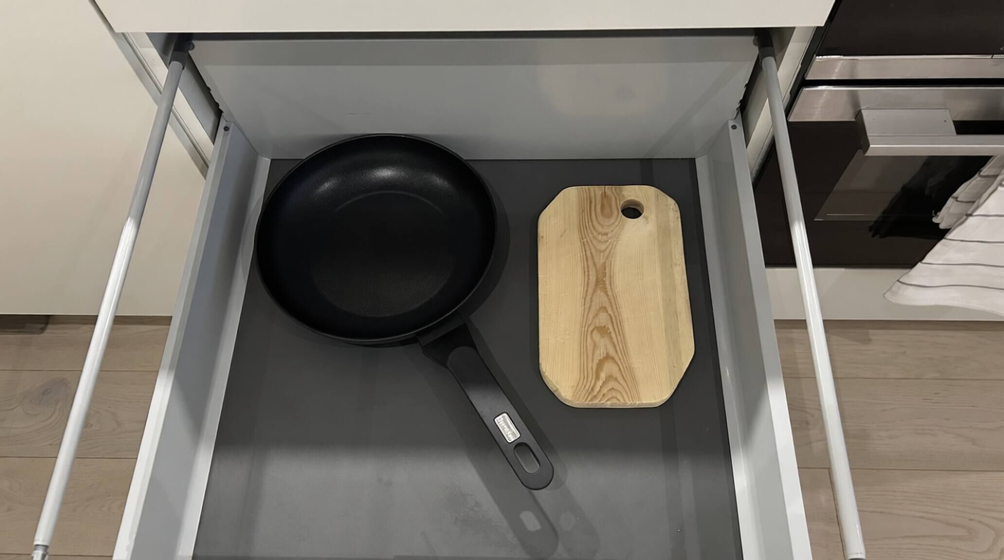 Eine Küchenschublade mit einer schwarzen Pfanne und einem Holzb schneidebrett.
