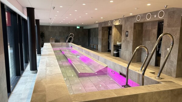 A modern bathroom with a long bench, a sink, and a mirror.