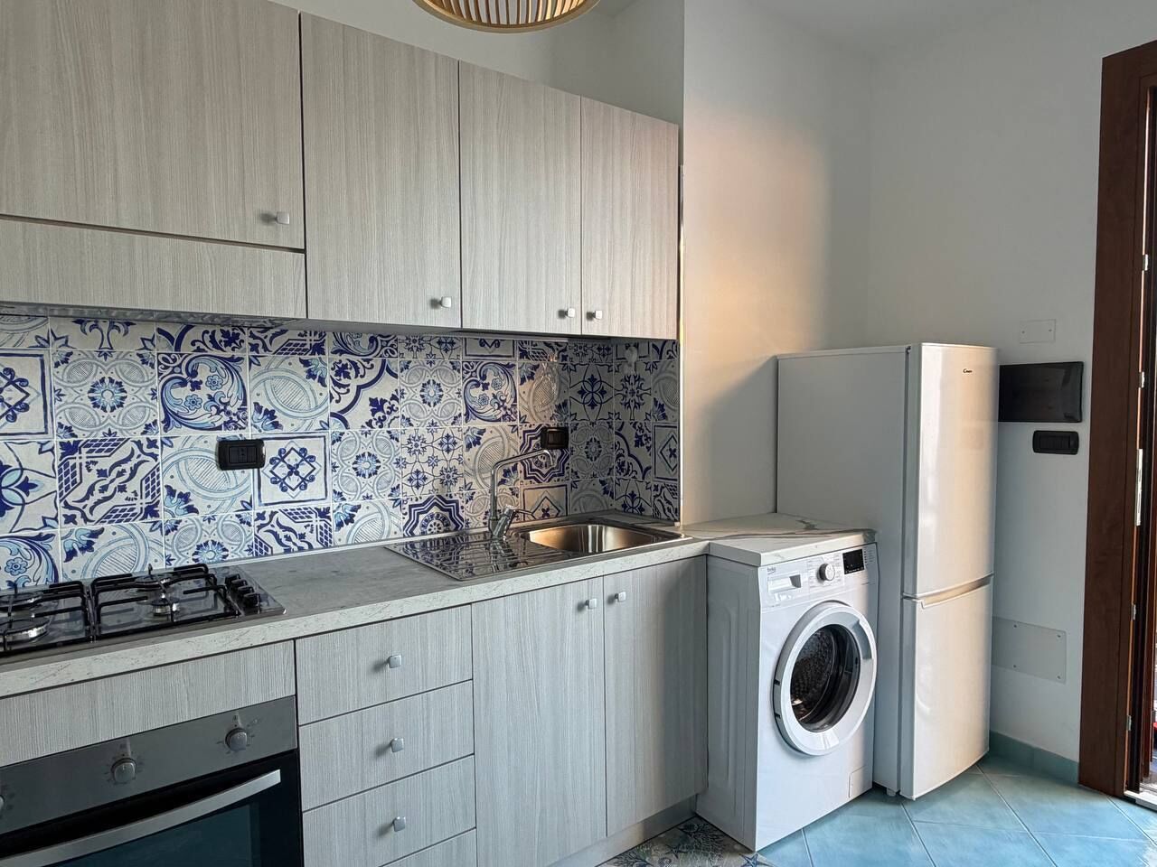 A compact kitchen with a washing machine, a stove, and a sink.