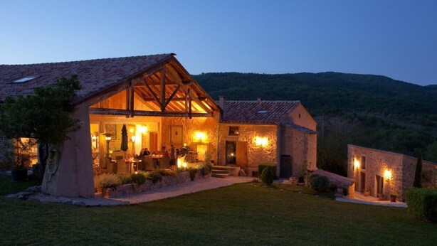 A stone building with a wooden facade, a covered patio, and a well-maintained lawn.