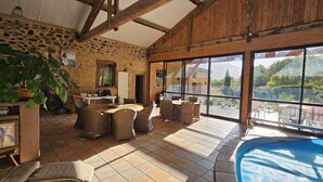 A spacious patio with wicker furniture, a pool, and a stone wall.