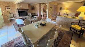 A rustic dining area with a stone fireplace, a staircase, and a cozy seating arrangement.