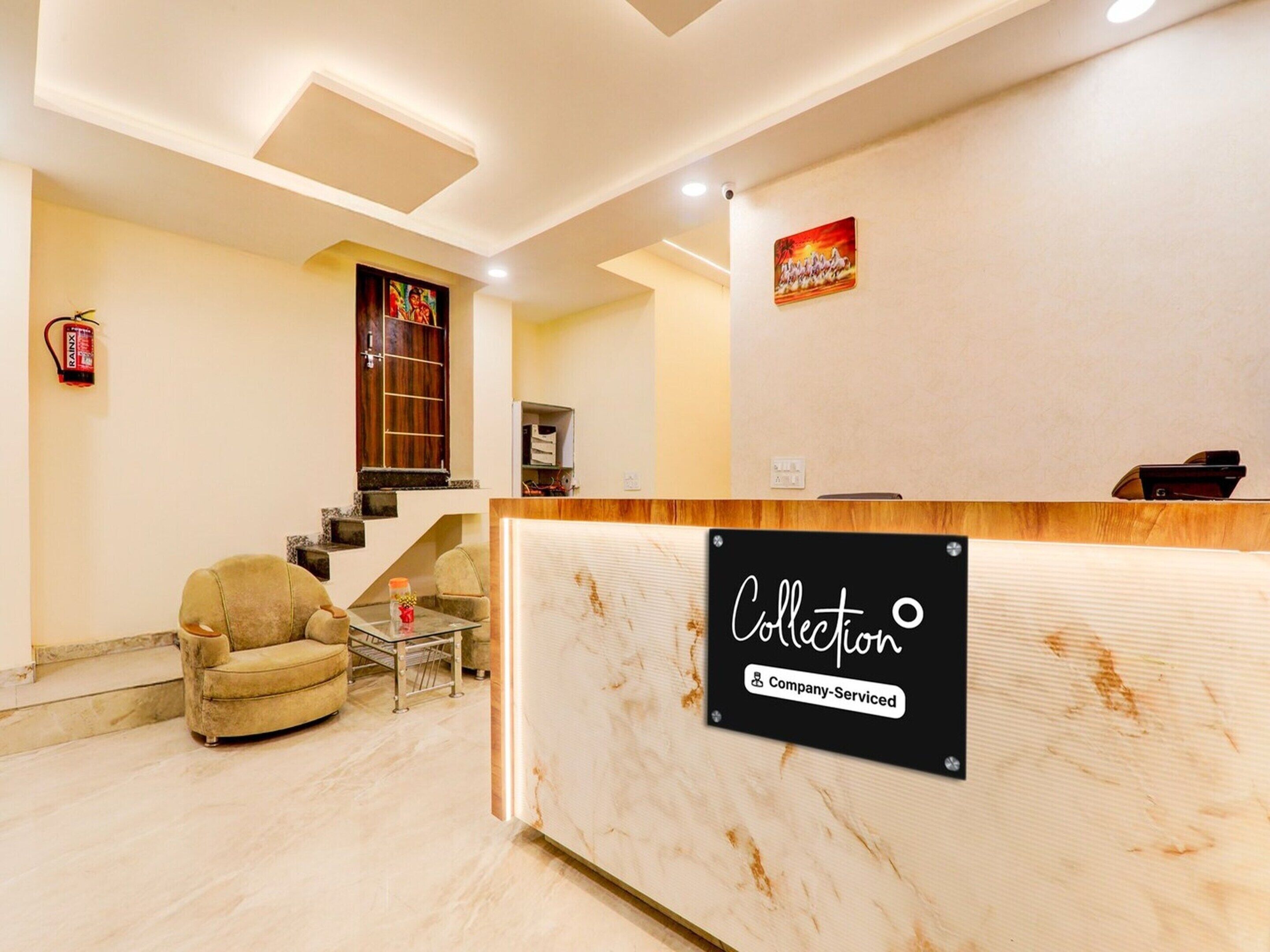 A hotel reception area with a marble reception desk, a sofa, a small table, and a fire extinguisher on the wall.