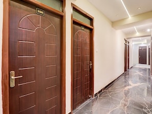 Two wooden doors with numbers 208 and 209, a marble floor, and a hallway with a ceiling light. - Deluxe Hotel Avon (Kanpur)
