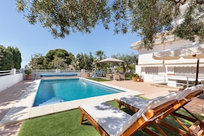 Ein Pool mit Liegestühlen, einer Pergola und einem weißen Gebäude mit Balkon.