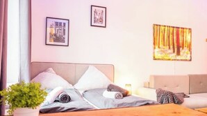 Une chambre à coucher avec un lit, une table de chevet, une plante en pot et un tableau accroché au mur.