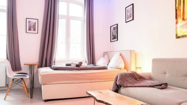 Une chambre à coucher avec un lit, un canapé, une chaise et une petite table.