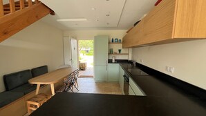 A compact kitchen with a dining area, a sofa, and a staircase. - 3 bedroom house and garden facing the beach. Arzon. Gulf of Morbihan (Arzon)