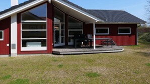 A red building with a large glass door, a covered porch, and a chimney. - 4 Star Holiday Home in Grossenbrode (Grossenbrode)