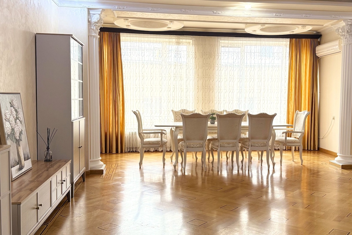 A dining area with a wooden floor, white chairs, a table, and a cabinet.