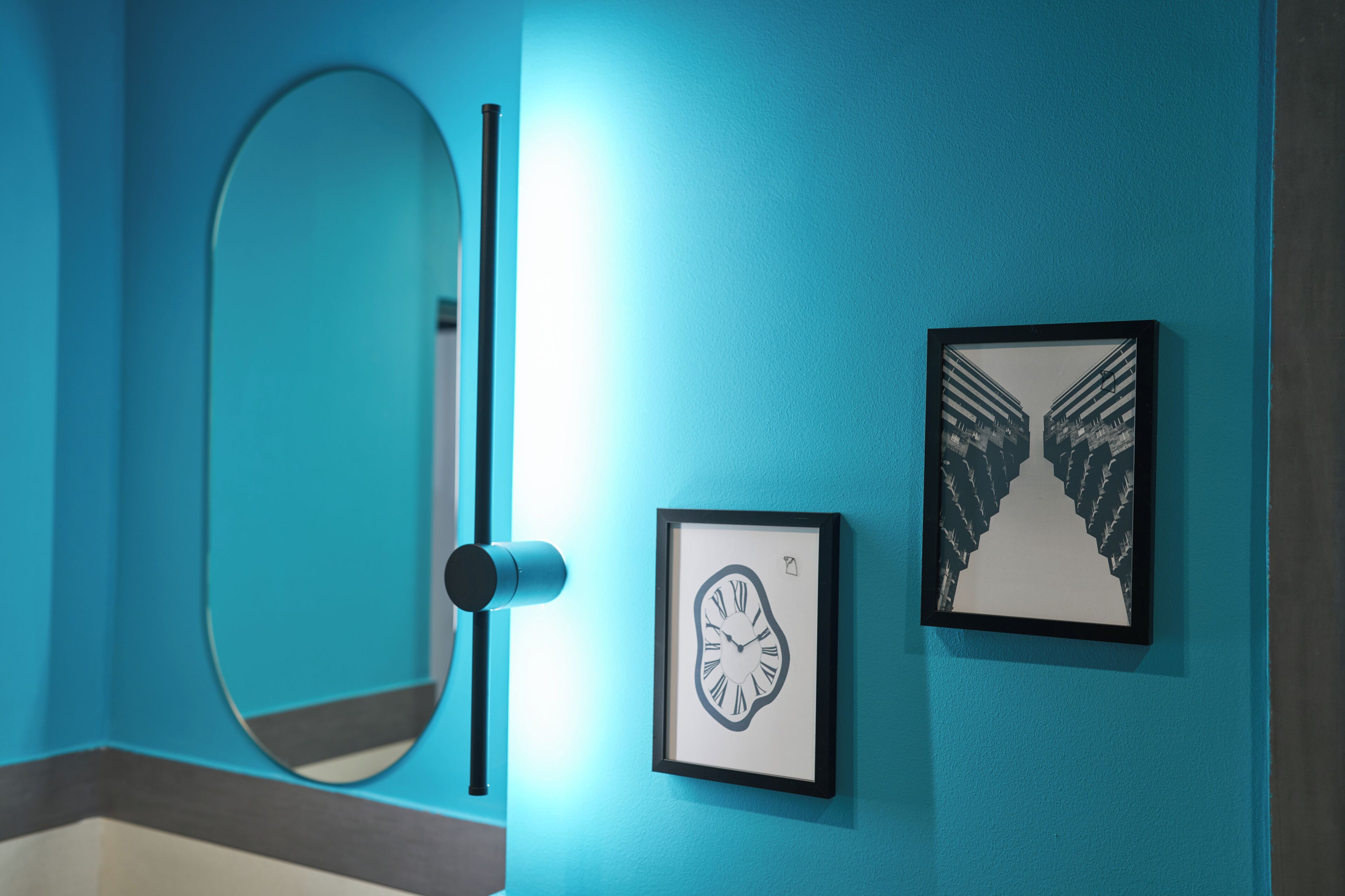 Une salle de bain avec un mur bleu, une horloge encadrée et un tableau encadré.