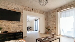 Una sala de estar moderna con una pared de piedra, un televisor de pantalla plana, una mesa de centro y un sofá.
