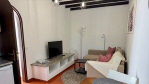 Una sala de estar con televisión, sofá y mesa de comedor.