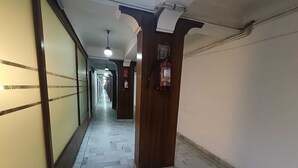 A hallway with a tiled floor, wooden pillars, and a fire extinguisher mounted on the wall. - Collection O Lansdowne Viewpoint (Lansdowne)