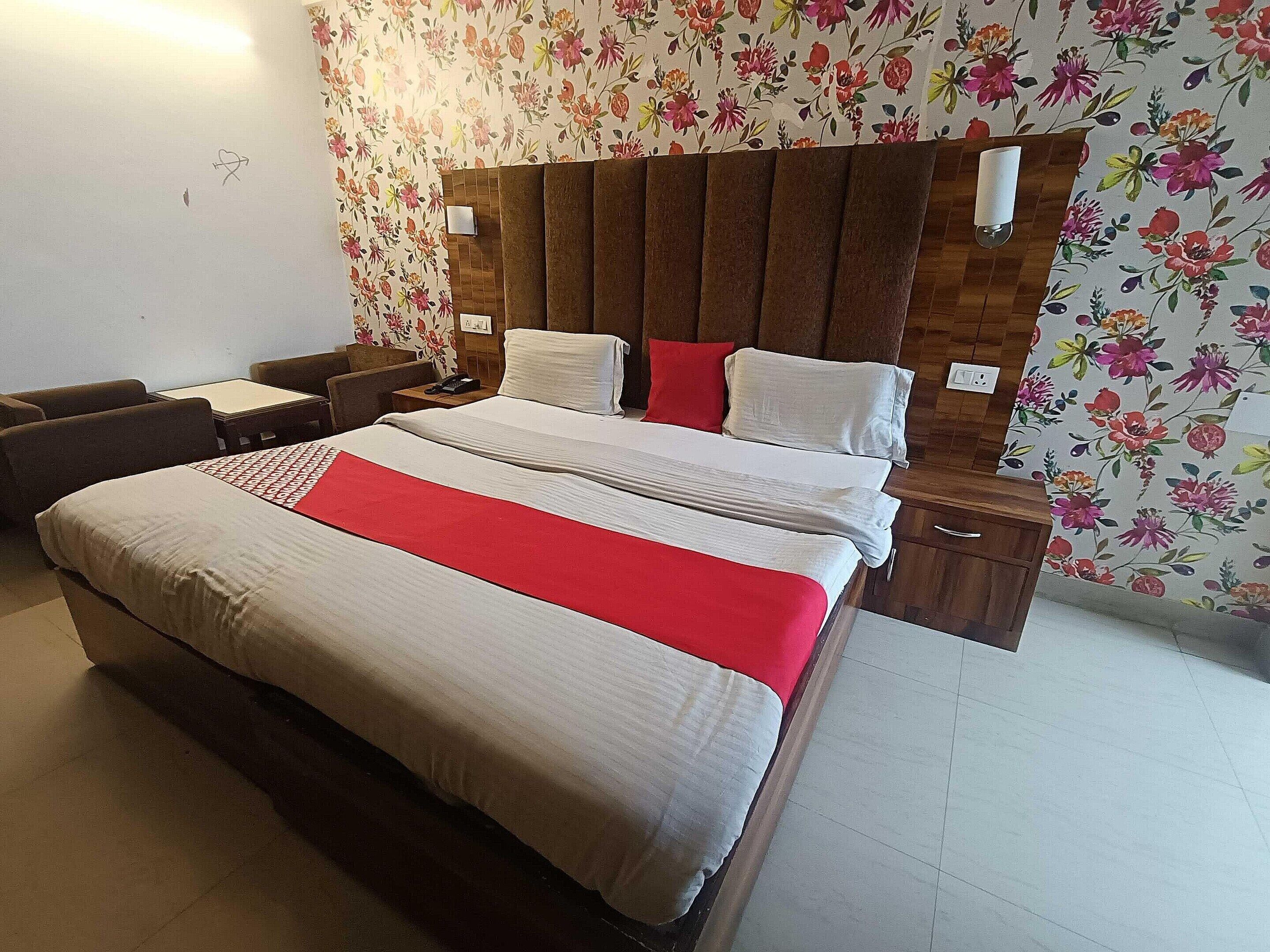 Une chambre d’hôtel avec un grand lit, une tête de lit en bois, une table de chevet, un bureau et une chaise.