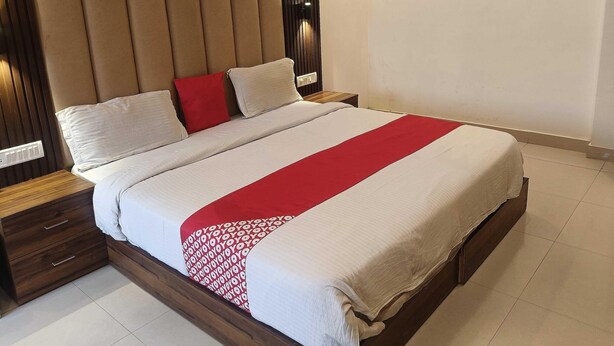 A neatly made bed with a red and white bedspread, wooden headboard, and a nightstand with a drawer. - Collection O Lansdowne Viewpoint (Lansdowne)