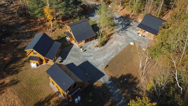 A cluster of cabins with a gravel driveway, surrounded by trees.