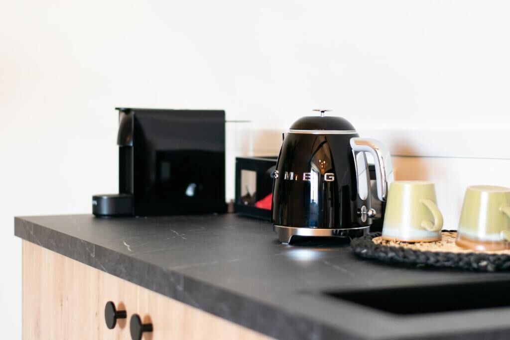 A kitchen counter with a coffee maker, two cups, and a black appliance.