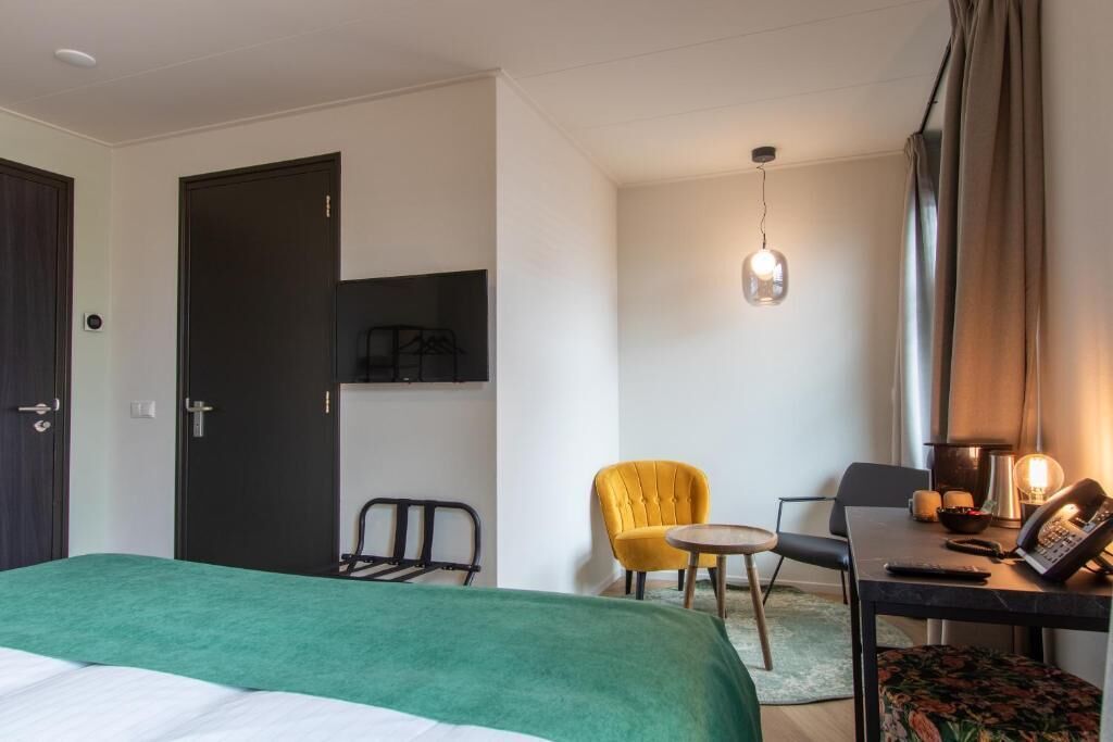 Una camera d'albergo con un letto, una scrivania con il telefono, una sedia e un tavolino.
