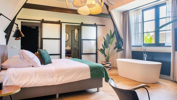 Een moderne slaapkamer met een bed, een groot raam, een badkuip en een plant.